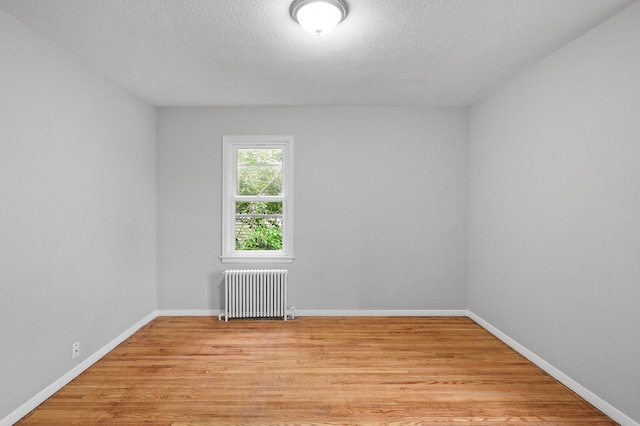 unfurnished room featuring radiator, light hardwood / wood-style floors, and a textured ceiling