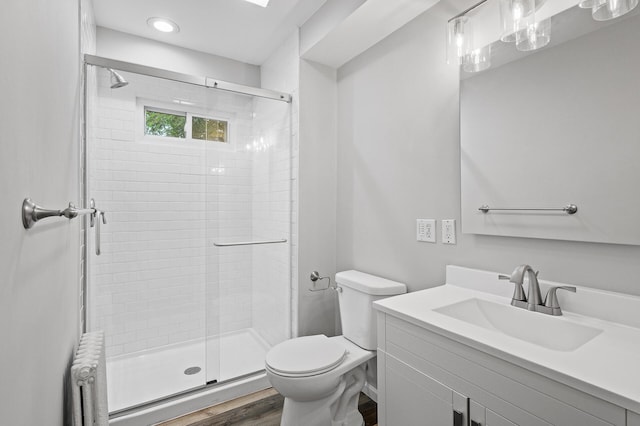 bathroom featuring radiator, wood-type flooring, vanity, an enclosed shower, and toilet