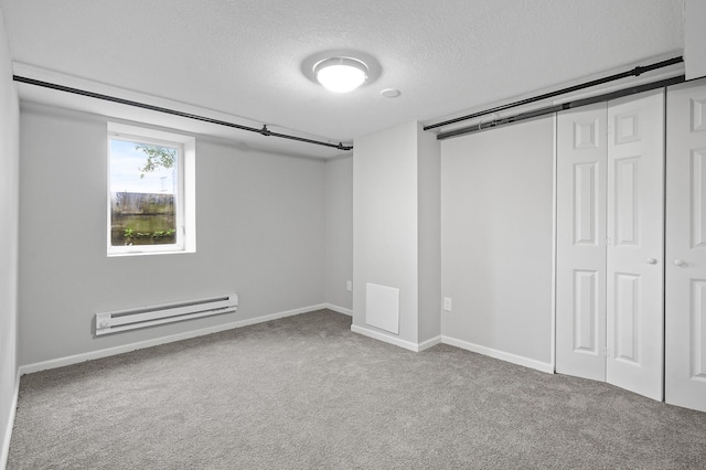 interior space with a barn door, a baseboard radiator, carpet, and a textured ceiling