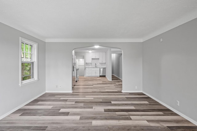 unfurnished living room featuring sink, a textured ceiling, and light hardwood / wood-style flooring