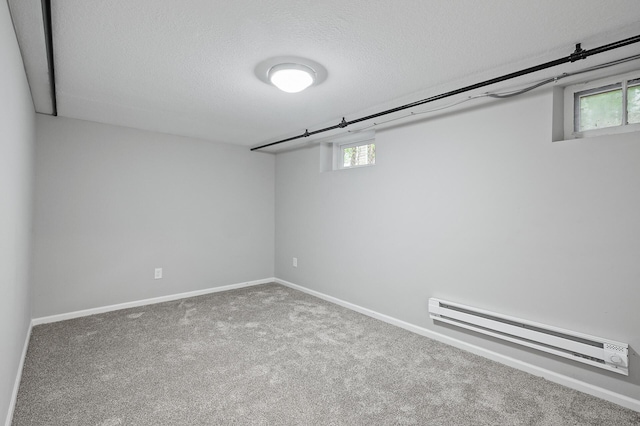 basement featuring carpet flooring, a textured ceiling, and baseboard heating