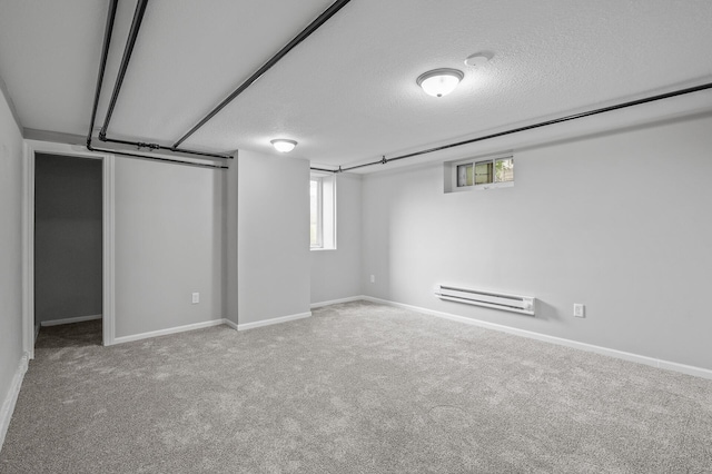 basement with a baseboard heating unit, a textured ceiling, and carpet