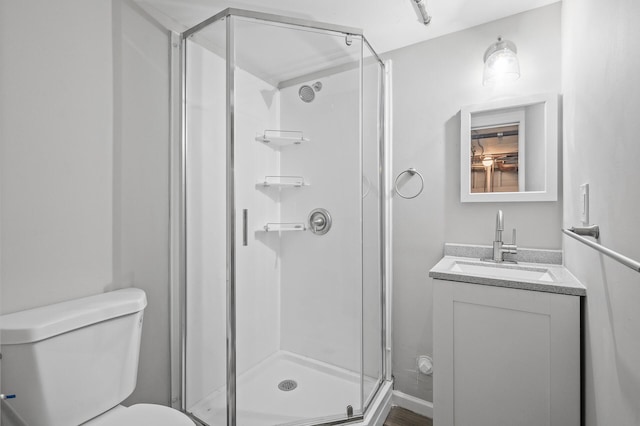 bathroom featuring vanity, a shower with shower door, and toilet