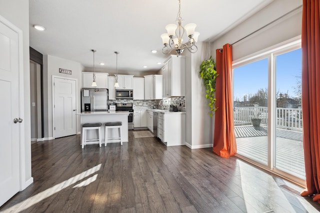 kitchen featuring pendant lighting, a breakfast bar area, stainless steel appliances, white cabinets, and a kitchen island