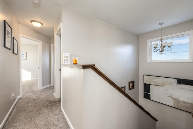 hall featuring an inviting chandelier and light carpet