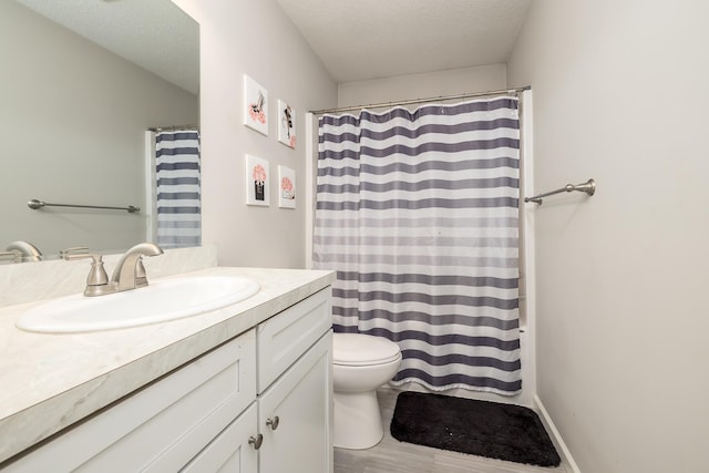 bathroom with vanity, toilet, and a textured ceiling