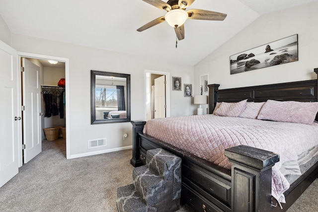 bedroom with lofted ceiling, ceiling fan, connected bathroom, a walk in closet, and light colored carpet