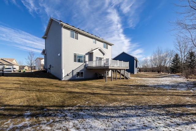 snow covered back of property with a wooden deck and a yard