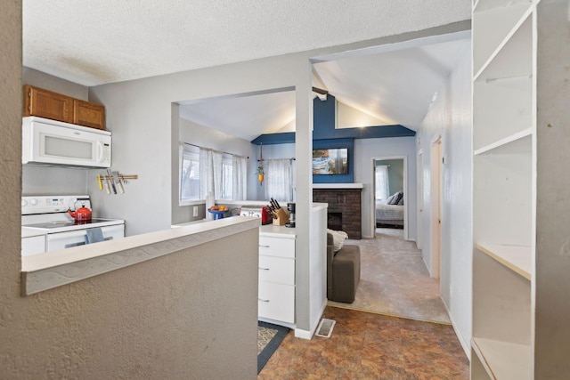 kitchen featuring lofted ceiling, white cabinets, white appliances, a brick fireplace, and a textured ceiling