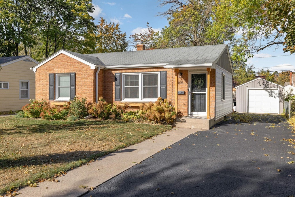 view of front facade with a garage, an outbuilding, and a front yard