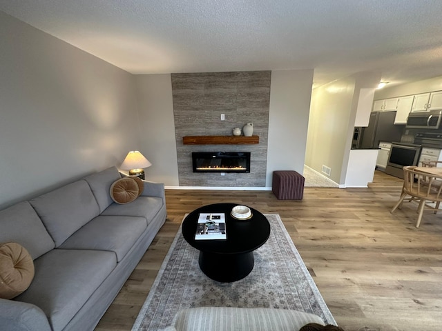 living room featuring a textured ceiling, a fireplace, and light hardwood / wood-style flooring