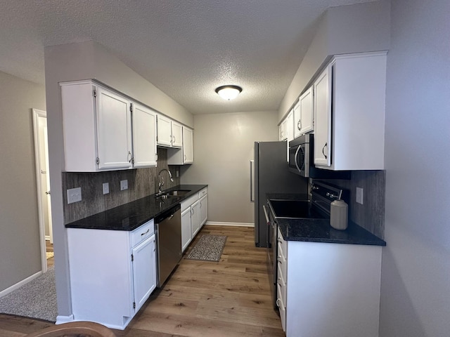 kitchen featuring sink, backsplash, stainless steel appliances, white cabinets, and a textured ceiling