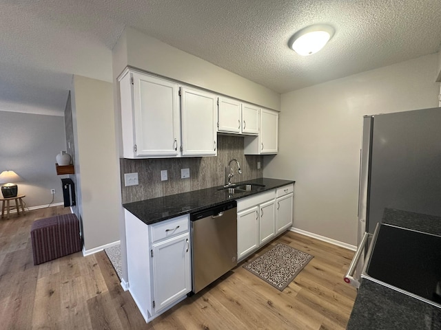 kitchen featuring sink, light wood-type flooring, appliances with stainless steel finishes, white cabinets, and backsplash