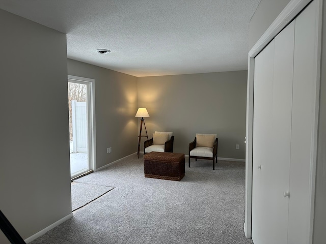 living area with light carpet and a textured ceiling