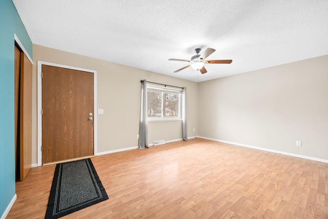 unfurnished room with ceiling fan, light hardwood / wood-style floors, and a textured ceiling