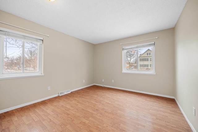 unfurnished room featuring light hardwood / wood-style flooring and a textured ceiling