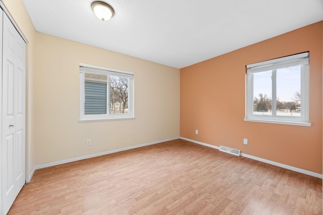 unfurnished bedroom with a textured ceiling, light hardwood / wood-style floors, and a closet