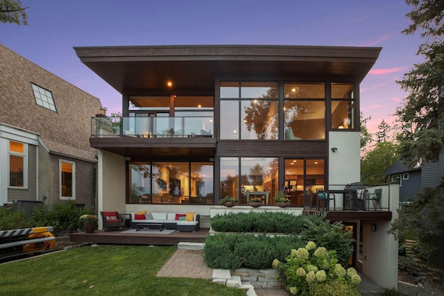 rear view of property with a yard, outdoor lounge area, and a balcony