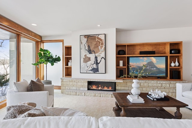 living area featuring recessed lighting, a glass covered fireplace, and carpet flooring