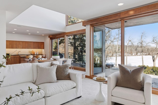 living area with plenty of natural light, light colored carpet, and recessed lighting