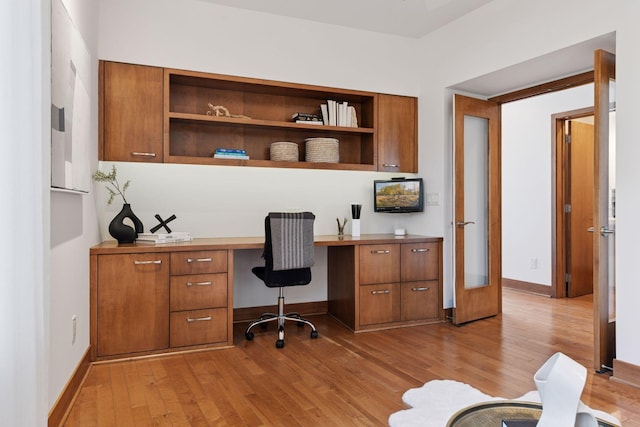 office featuring light wood-style floors, baseboards, and built in study area