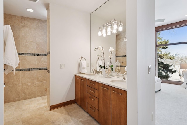 full bath with a walk in shower, baseboards, double vanity, ensuite bath, and a sink