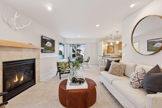 living room featuring recessed lighting, a fireplace, light colored carpet, and baseboards