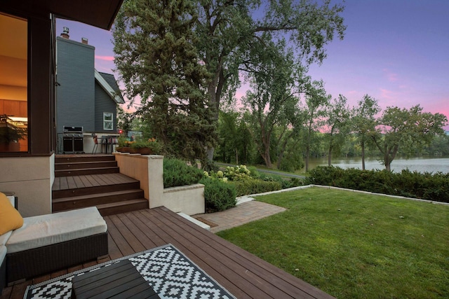 yard at dusk featuring a deck with water view