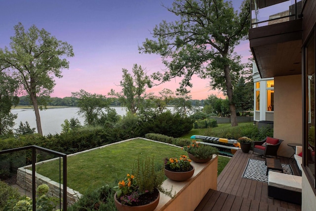 yard at dusk featuring a water view and a balcony