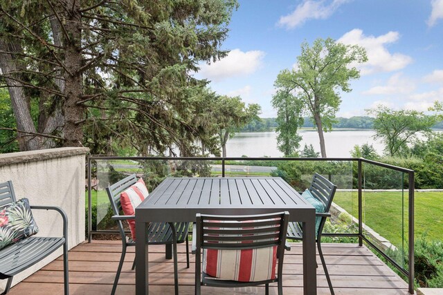 wooden deck with a yard, a water view, and outdoor dining area