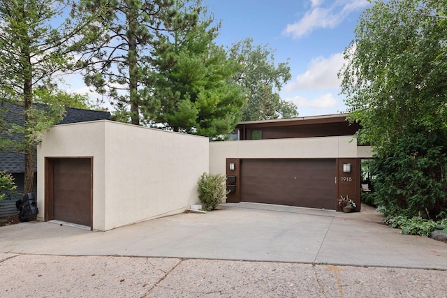 view of front of house featuring stucco siding, concrete driveway, a garage, and roof with shingles