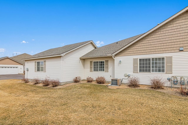 101 Bridgewater Trl, Hudson, WI 54016 - back of house featuring central AC unit, roof with shingles, a lawn, and a garage