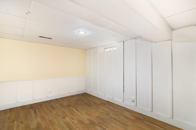 basement with a drop ceiling and wood-type flooring