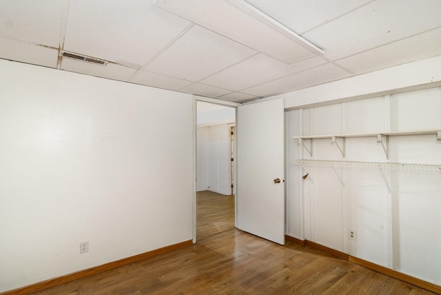 basement with a drop ceiling and hardwood / wood-style floors