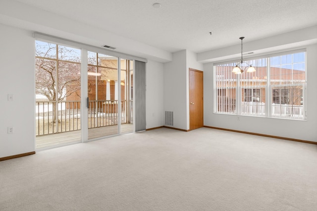 unfurnished room featuring carpet flooring, a textured ceiling, and an inviting chandelier