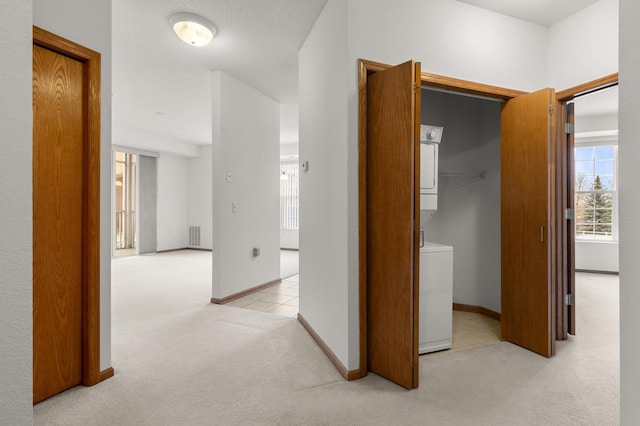 hallway featuring stacked washer and dryer and light carpet