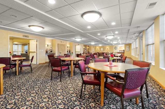 dining space with carpet flooring and a drop ceiling