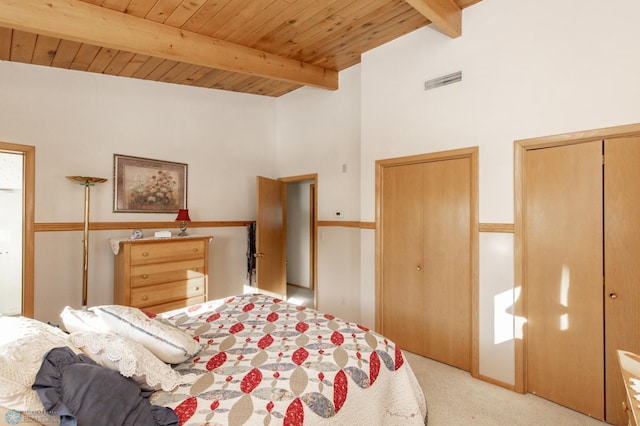 bedroom featuring lofted ceiling with beams, wooden ceiling, two closets, and light colored carpet