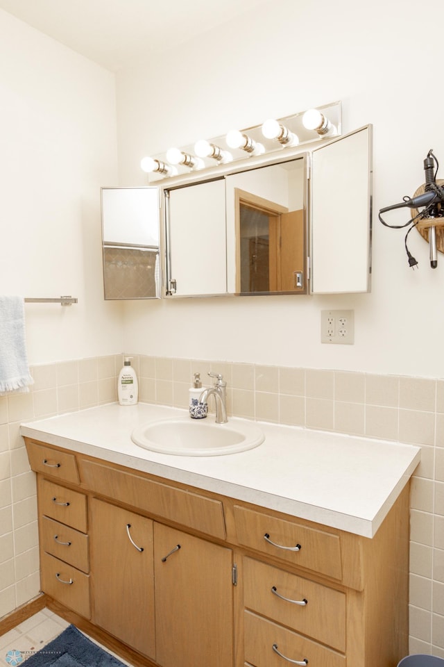 bathroom with tile walls, vanity, and tile patterned flooring