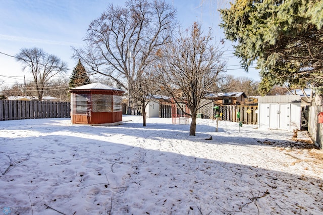 snowy yard featuring a gazebo and a storage unit