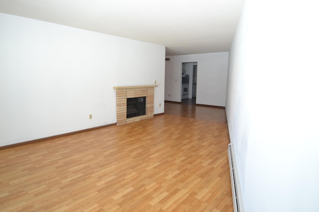 unfurnished living room featuring a brick fireplace, light hardwood / wood-style flooring, and baseboard heating