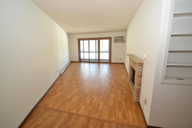 unfurnished living room featuring an AC wall unit, built in features, a baseboard heating unit, light hardwood / wood-style floors, and a brick fireplace