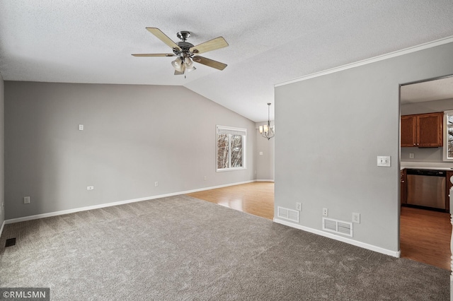 unfurnished living room with ceiling fan with notable chandelier, lofted ceiling, carpet floors, and a textured ceiling