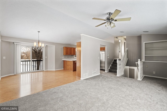 unfurnished living room featuring lofted ceiling, ceiling fan with notable chandelier, and light colored carpet