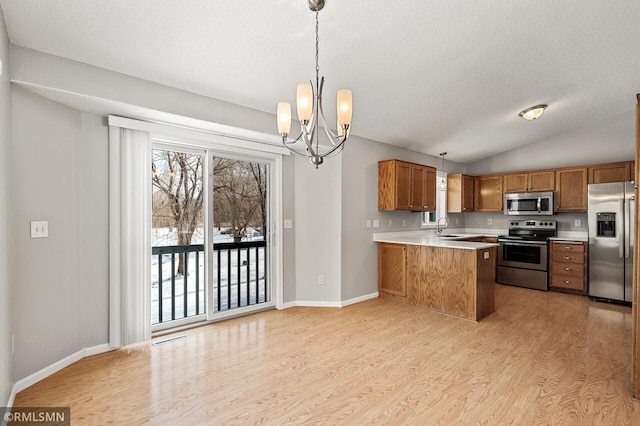 kitchen with appliances with stainless steel finishes, kitchen peninsula, sink, and hanging light fixtures