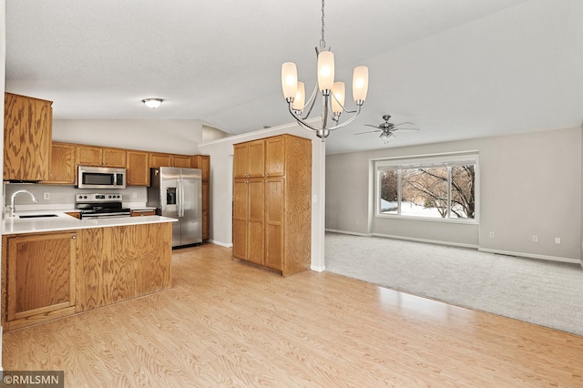 kitchen featuring decorative light fixtures, sink, light hardwood / wood-style floors, kitchen peninsula, and stainless steel appliances