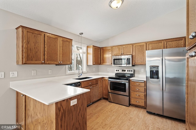 kitchen with sink, appliances with stainless steel finishes, light hardwood / wood-style floors, decorative light fixtures, and kitchen peninsula