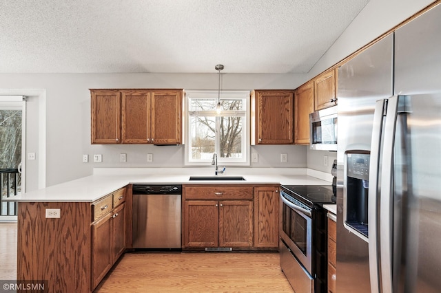 kitchen featuring pendant lighting, sink, stainless steel appliances, a textured ceiling, and kitchen peninsula