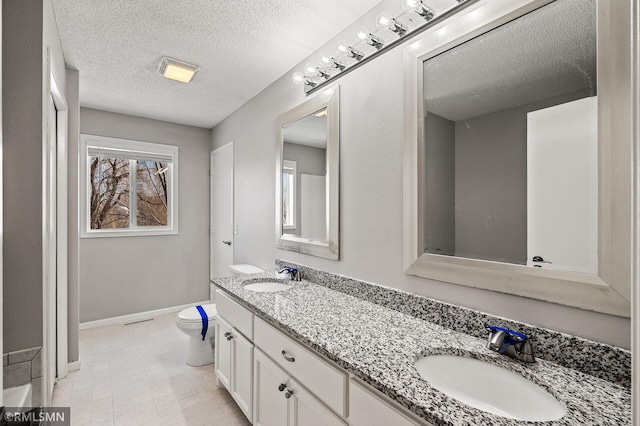 bathroom with vanity, toilet, and a textured ceiling