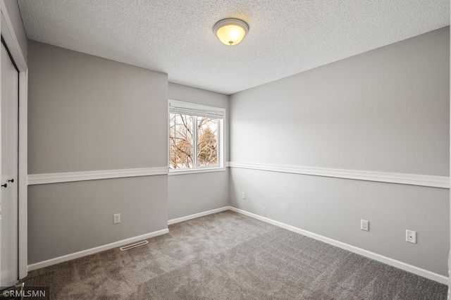 carpeted empty room featuring a textured ceiling